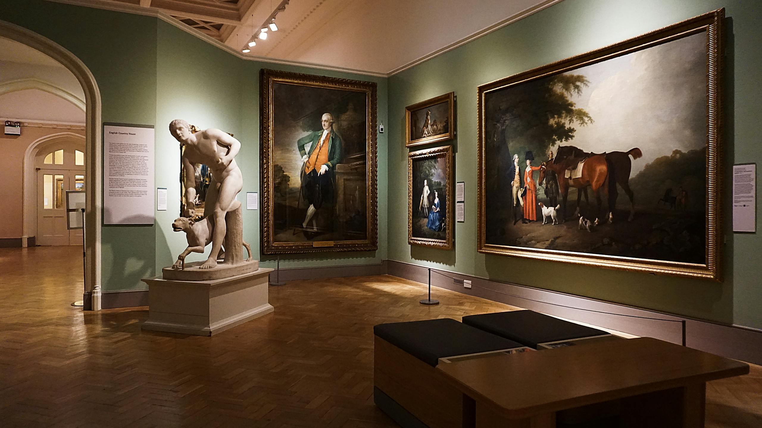 An elegant art gallery room featuring classical paintings and a prominent marble statue.
